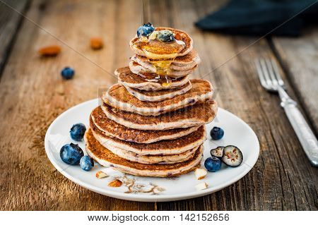 Stack of pancakes. Healhy oat pancakes with blueberries and honey on plate on wooden table