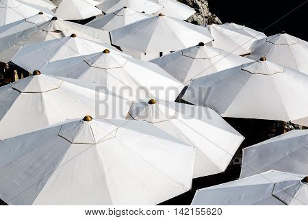 Many white sun umbrellas seen from above.
