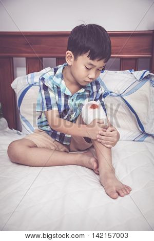 Child Injured. Wound On The Child's Knee With Bandage. Vintage Tone.