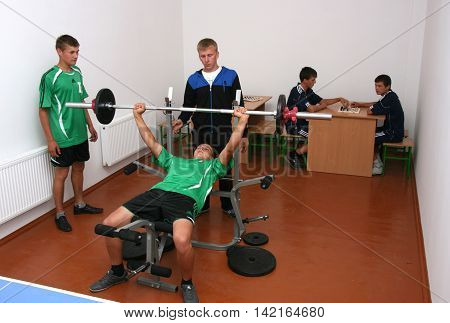 MULCHYCI UKRAINE - September 04 2012: Teenager is working out chest with barbell in a school gym during physical education classes