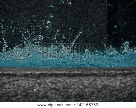 Water splashes out of a waterspout fountain and splashes into the water basin