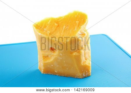 piece of solid gauda cheese on blue board
