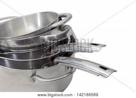 Fragment of a stack of stainless steel stock pots and other cooking utensil with various handles oon a light background