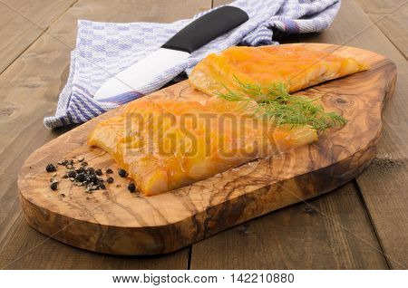 fresh smoked scottish haddock with dill on a wooden board
