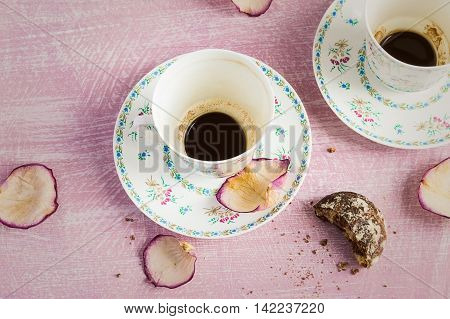 Two empty coffee cups and rose petals.