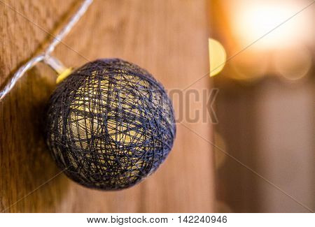 Decorative light fixture, cotton ball on string against a wooden background