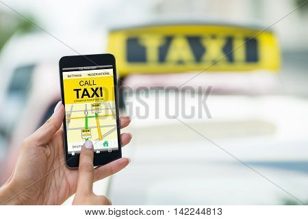 Close-up Of A Female's Hand Holding Mobile Phone Booking Taxi