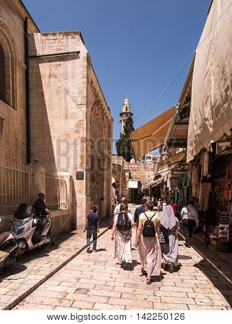Jerusalem Israel - July 15 2015: Narrow stone street among stalls with traditional souvenirs and goods at bazaar in Old City and children at play - popular place among tourists and pilgrims visiting Jerusalem.