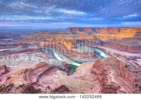 Sunrise illuminates clouds and the canyon walls of this colorful sunrise scene from Deadhorse Point. Deadhorse Point State Park is adjacent to Canyonlands National Park and near Moab Utah.
