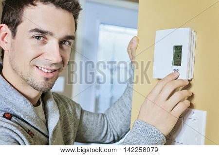 A man set the thermostat at house.