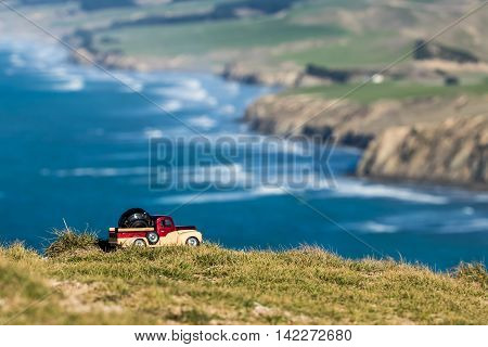 Pickup truck carrying a camera lens with a New Zealand coastline in the background.