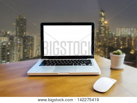 Front view of laptop on table in Office and night building blurred background
