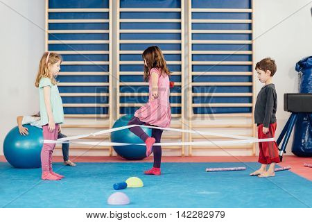Little children playing with elastic band on physical education class