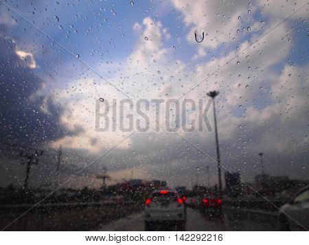 Raindrop On A Glass With Traffic Light And Beautiful Blured Blue Sky And Cloud In Background