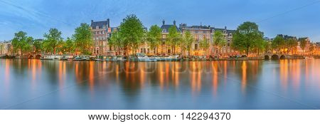 Panoramic view and cityscape of Amsterdam with boats, old buildings and Amstel river, Holland, Netherlands.