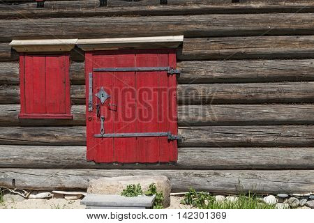 Red old door and window on the wooden wall of a village house. Excellent background