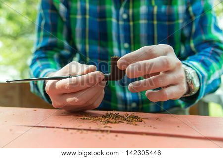 Close-up photo of man who fills his pipe with tobacco