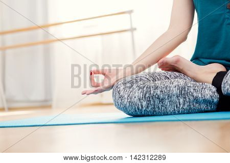 Woman sitting in lotus position idoors, hands closeup. Meditating and relaxing