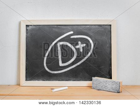 Grade d plus write on dirty blackboard chalk and eraser on wood table over white cement background