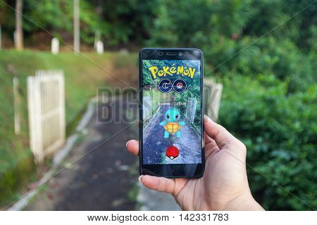 California, United States - July 23, 2016: Close up of a man holding a smartphone while playing Pokemon Go game and try to catch a Pokemon.