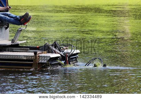 mini dredger is clearing lake algae summer day