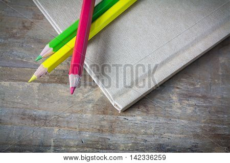 Color Pencils over notebook on wood table