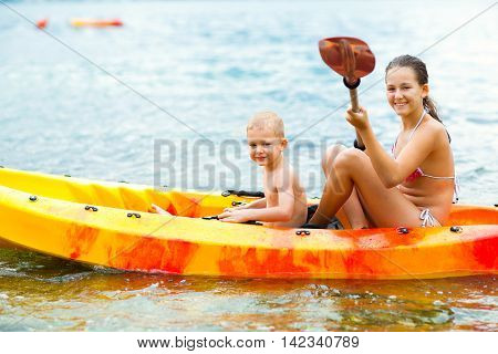 Kids enjoying paddling in kayak on the sea water during summer vacation