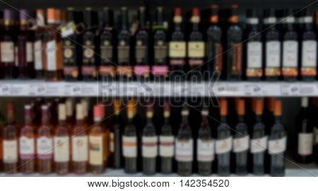 Out of focus supermarkt shelves with bottles of red and white wine.