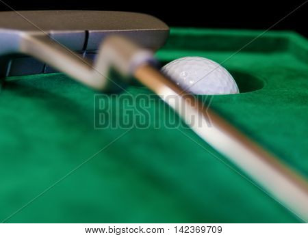 indoor mini golf ball pocket and putter on green cloth
