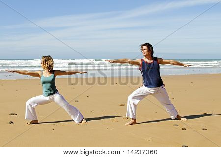 Jong koppel doen yoga oefeningen op het strand