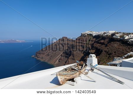 Old wooden rowing boat overlooking Santorini's bay