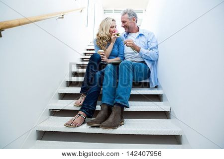 Happy man giving flower to woman on steps at home