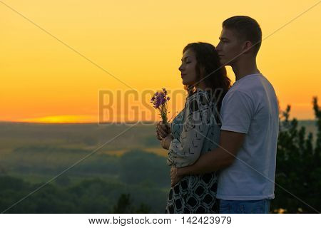 romantic couple look on sunset on country outdoor, beautiful landscape and bright yellow sky, love tenderness concept, young adult people