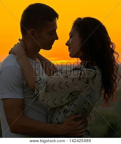 romantic couple embrace at sunset on outdoor, beautiful landscape and bright yellow sky, love tenderness concept, young adult people