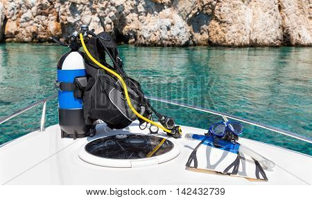 Scuba diving equipment on a boat in front of the emerald waters of the mediterranean sea