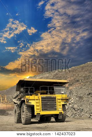 Heavy dump truck transporting iron ore from the opencast on sunset