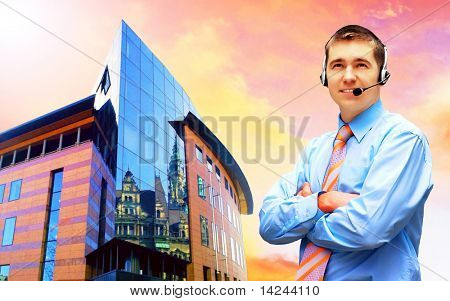 Homme d'affaires de bonheur en headphoness sur le fond d'architecture d'entreprise