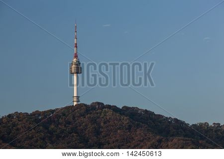 View to N Seoul Tower dominating over forested hill. It is a communication and observation tower in city center at 236 m height. South Korea