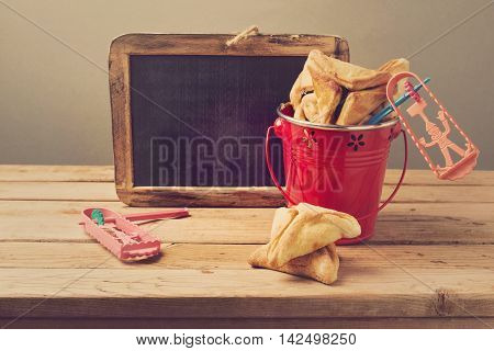 Hamantaschen cookies in bucket with grogger and chalkboard