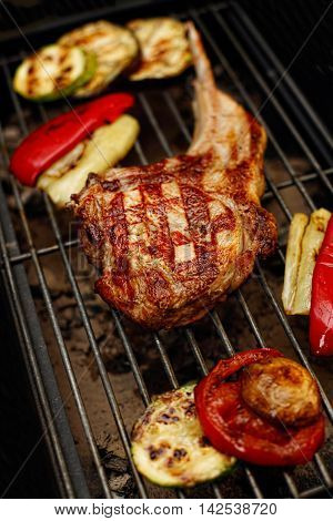 Rib steak on a grill with vegetables