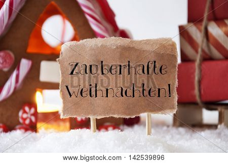Gingerbread House In Snowy Scenery As Christmas Decoration. Sleigh With Christmas Gifts Or Presents. Label With German Text Zauberhafte Weihnachten Means Magic Christmas
