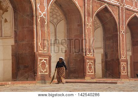 DELHI INDIA - NOVEMBER 4: Unidentified woman sweeps at Humayun's Tomb on November 4 2014 in Delhi India. Humayun's Tomb was the first garden-tomb on the Indian subcontinent.
