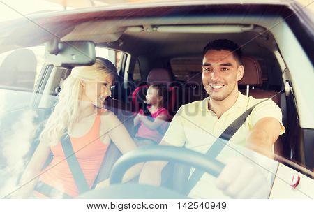 family, transport, safety, road trip and people concept - happy man and woman with little child driving in car