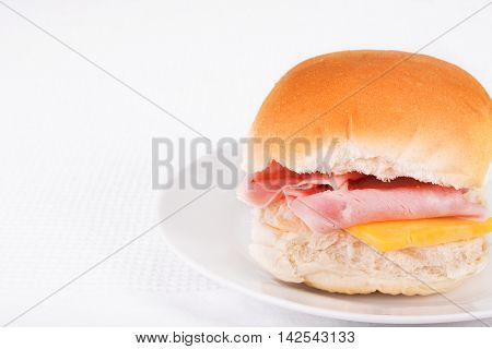 Ham and cheese bread roll or bap on a white plate
