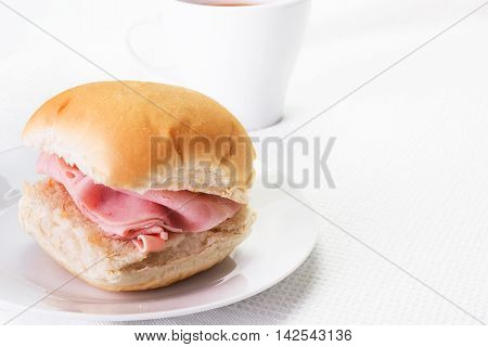 Ham bread roll or bap and a hot drink