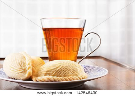 Traditional Azerbaijani sweet pastry shekerbura on a plate with tea. Eaten at Novruz spring holiday