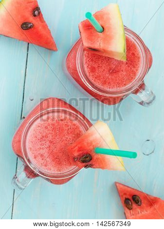 Watermelon smothie and slices on soft blue wooden background. Flat lay or top view. Vertical