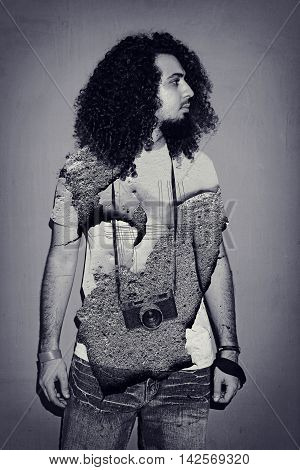 Closeup of one handsome passionate expressive cool young brunette photographer men with long curly hair holding a vintage SLR camera standing against red background