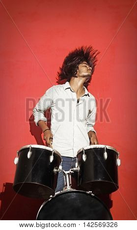 young drummer head banging isolated on red background