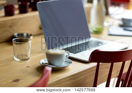 laptop with fresh cup of coffee in coffee shop